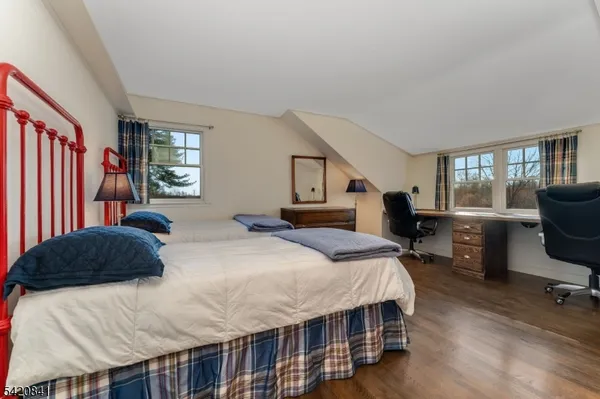 a bedroom with a bed a dresser and a large window