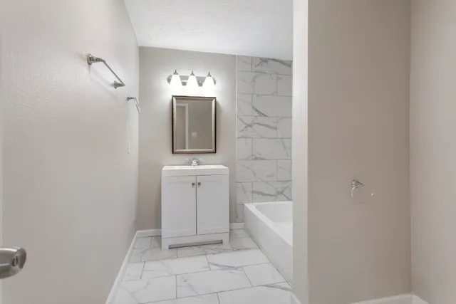 a bathroom with a bathtub sink and mirror
