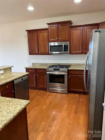 a kitchen with stainless steel appliances granite countertop a stove a sink and a microwave