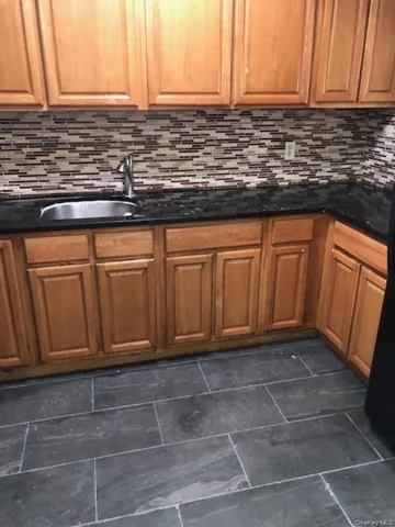 a kitchen with granite countertop a sink a stove and wooden cabinets