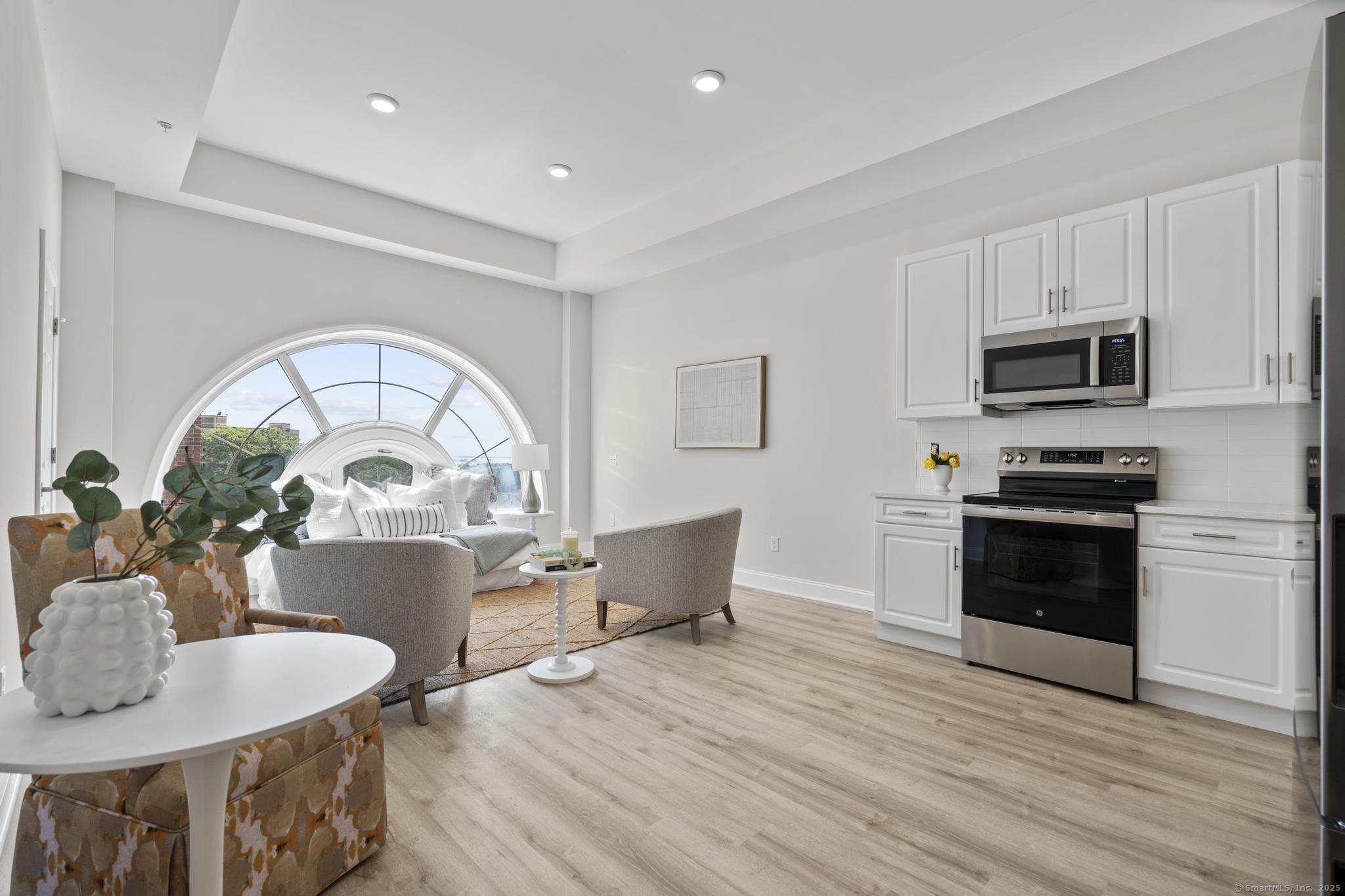 120 Broad Street, Unit 407 New London, CT 06320 - Photo 4 of 18 a kitchen with sink a microwave dining table and chairs