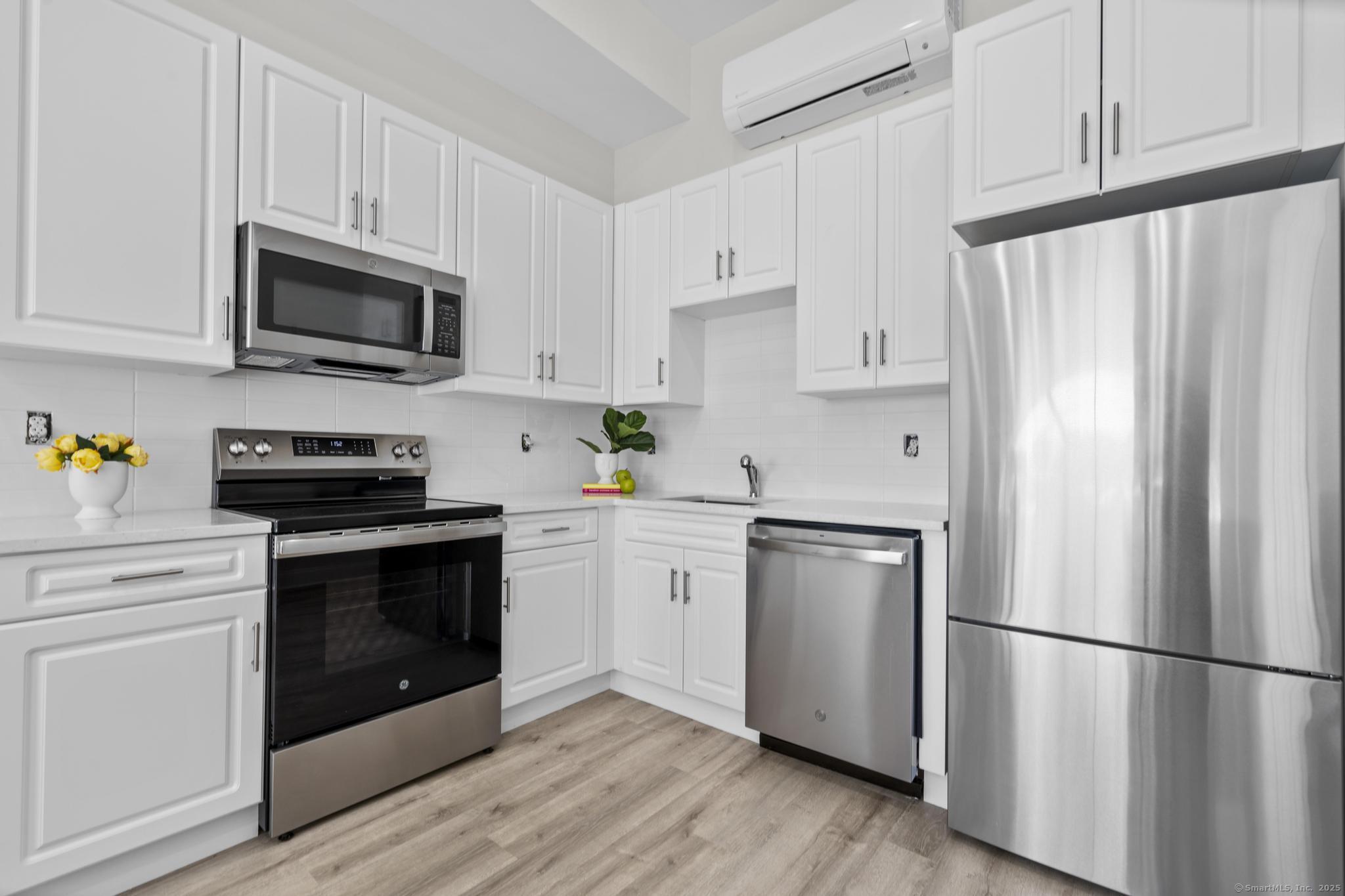 120 Broad Street, Unit 407 New London, CT 06320 - Photo 5 of 18 a kitchen with stainless steel appliances a refrigerator stove and white cabinets