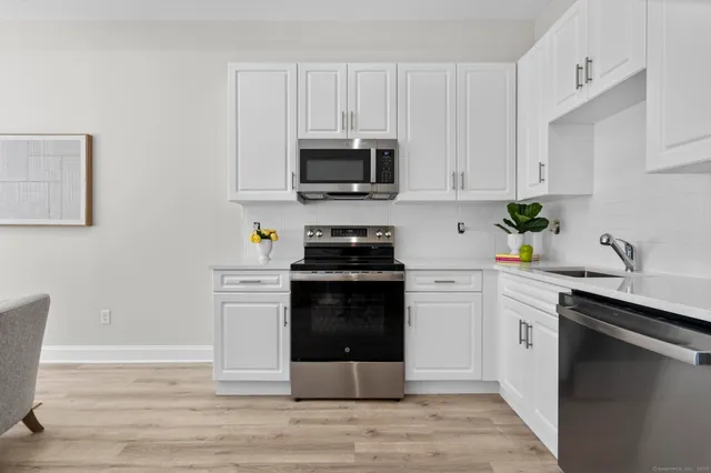 a kitchen with cabinets stainless steel appliances a sink and wooden floor