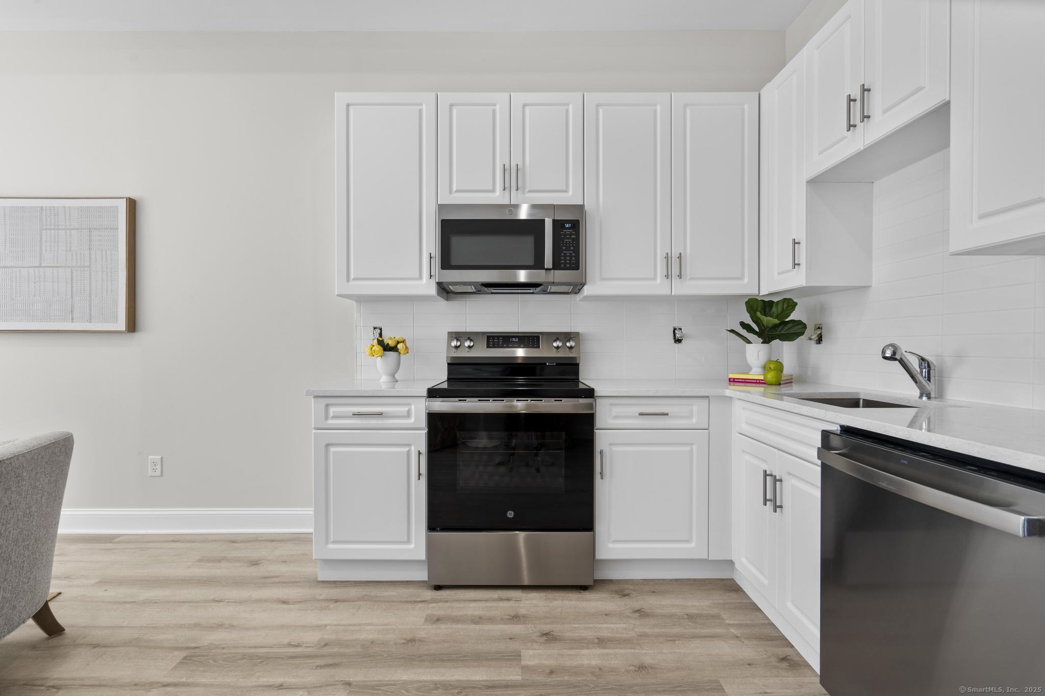 120 Broad Street, Unit 407 New London, CT 06320 - Photo 7 of 18 a kitchen with cabinets stainless steel appliances a sink and wooden floor