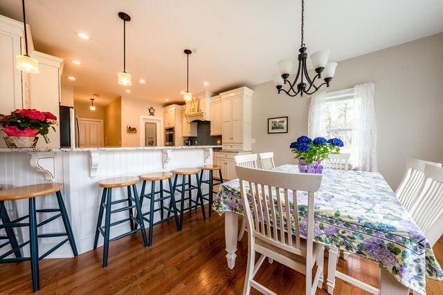a view of a dining room and livingroom with furniture wooden floor a chandelier