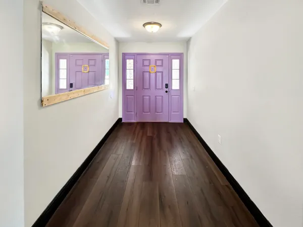 a view of a hallway with wooden floor and a window