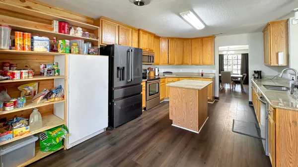 a kitchen with stainless steel appliances granite countertop a refrigerator a stove and a wooden floors