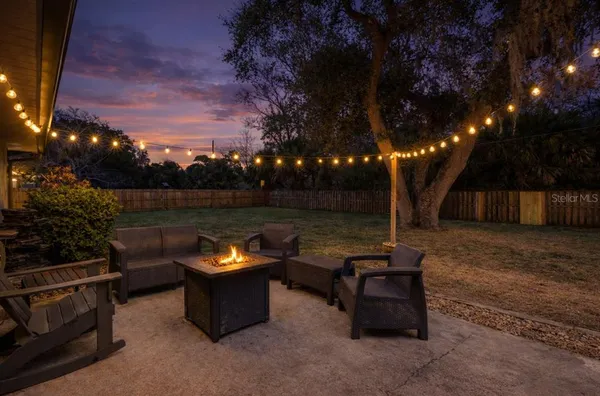 a view of a backyard with couches and a fire pit and a large tree