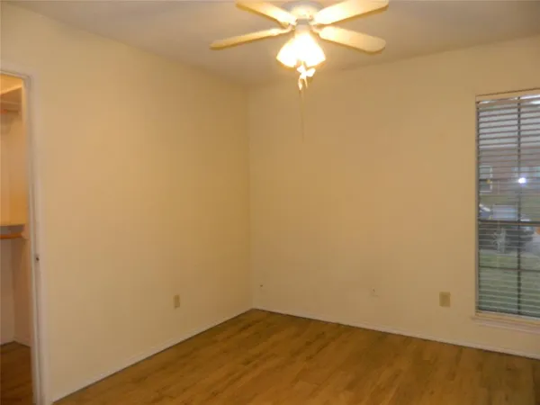 an empty room with windows and fan