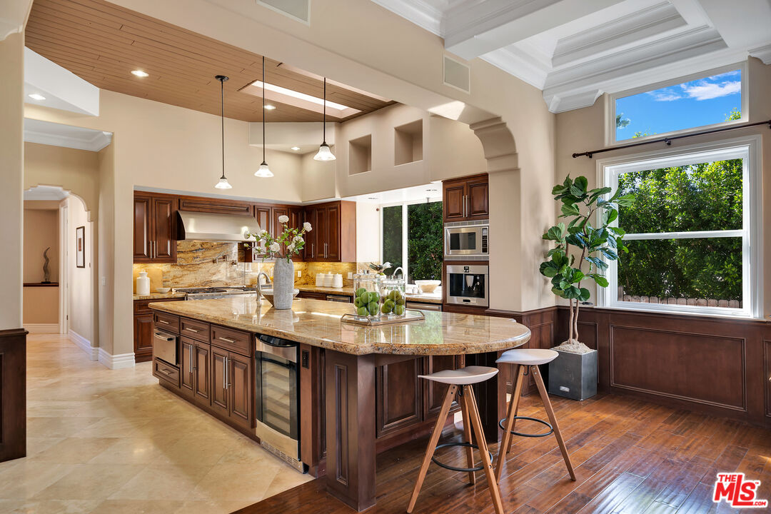 19261 Wells Drive Tarzana, CA 91356 - Photo 31 of 51 a kitchen with stainless steel appliances granite countertop a kitchen island a stove a table and chairs in it