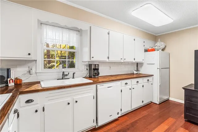 a kitchen with granite countertop white cabinets white appliances and sink