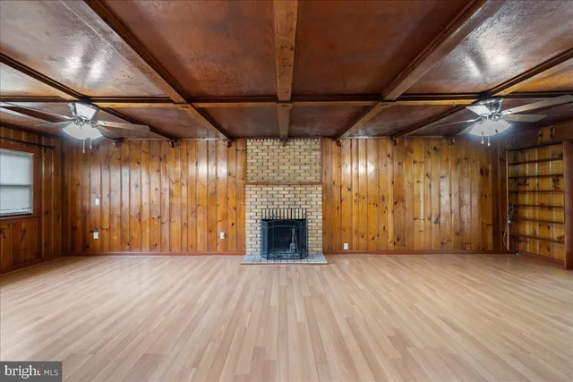 an empty room with wooden floor fireplace and windows