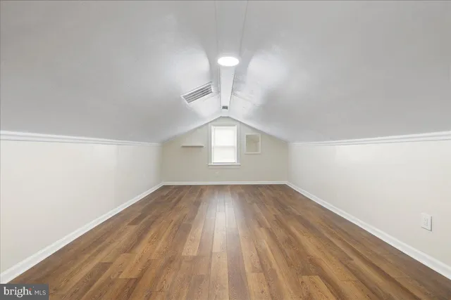 an empty room with wooden floor cabinet and windows