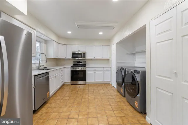 a large kitchen with stainless steel appliances granite countertop a sink a stove a refrigerator and cabinets