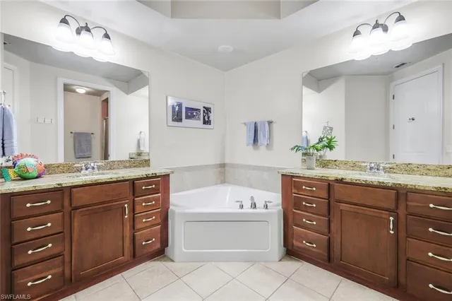 a bathroom with a granite countertop bathtub sink double vanity and mirror
