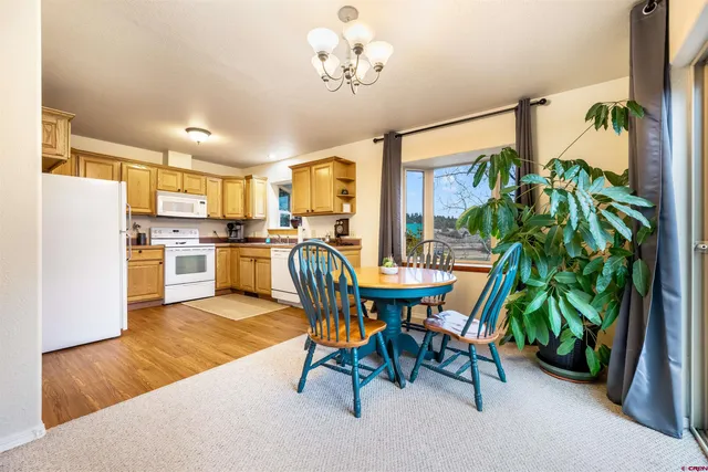 a dining room filled a chandelier and kitchen view