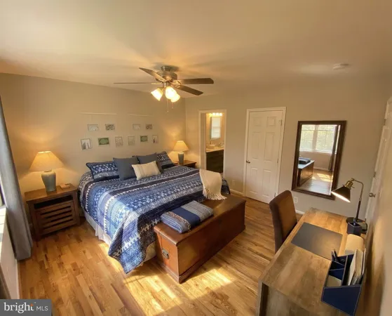 a bedroom with a bed ceiling fan and a wooden floor