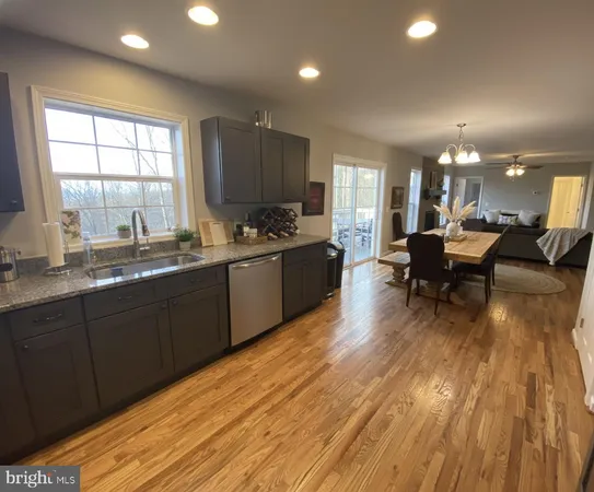 a living room with stainless steel appliances granite countertop a sink dishwasher a stove and a refrigerator with wooden floor