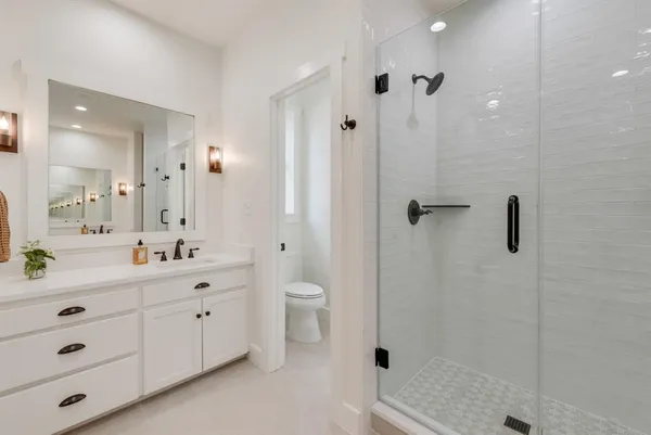 a bathroom with a double vanity sink toilet a shower and a mirror
