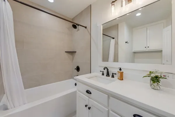 a bathroom with a bathtub shower sink and vanity