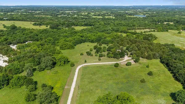 an aerial view of residential houses with outdoor space and trees