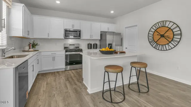 a kitchen with stainless steel appliances granite countertop a table chairs refrigerator and sink