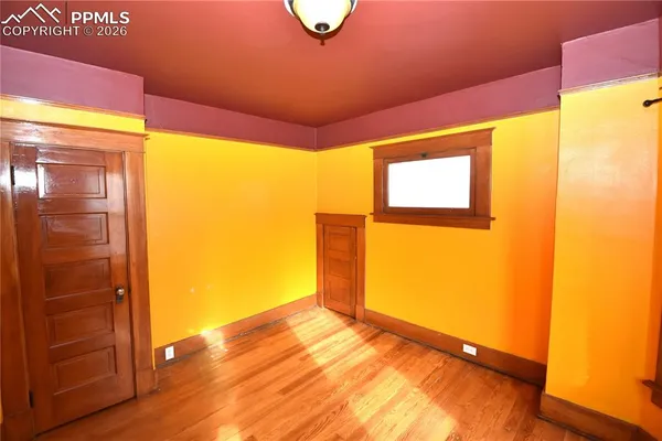 a view of an empty room with wooden floor and a window