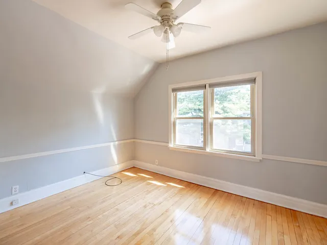 an empty room with a window and wooden floor