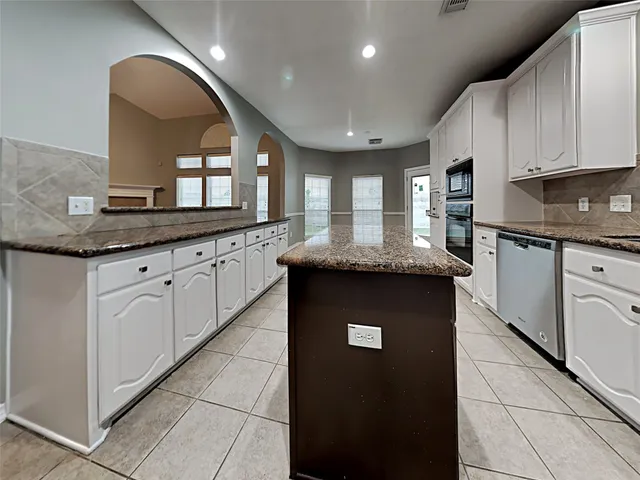 a kitchen with granite countertop kitchen island a sink stainless steel appliances and cabinets