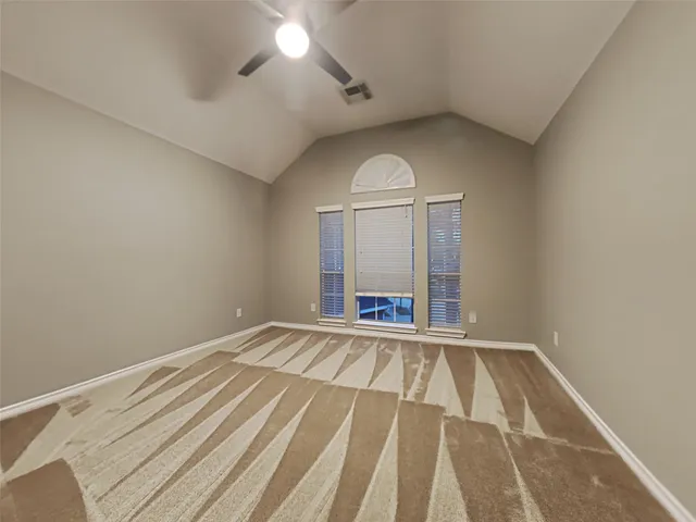 an empty room with wooden floor fan and window