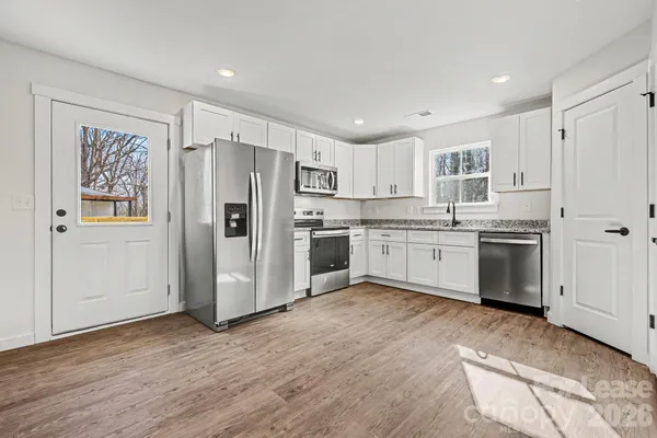 a kitchen with granite countertop white cabinets stainless steel appliances and a sink