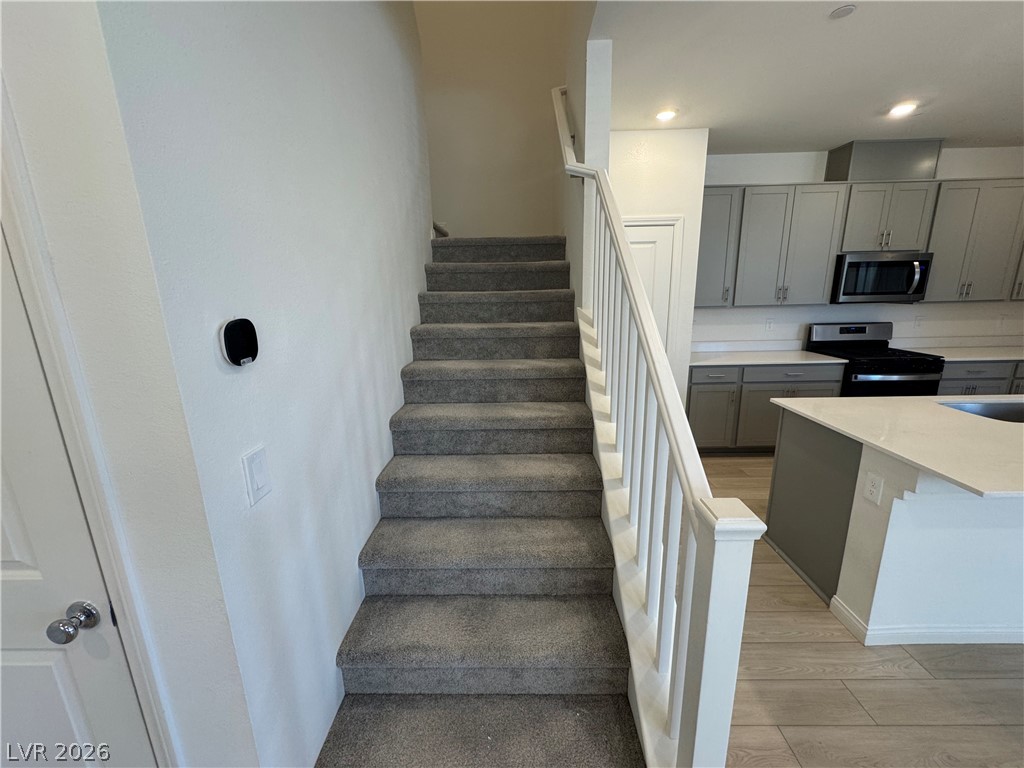 2821 Alcobaca Street Henderson, NV 89044 - Photo 11 of 24 A well-appointed kitchen featuring sleek cabinetry and modern appliances, conveniently located adjacent to a carpeted staircase.