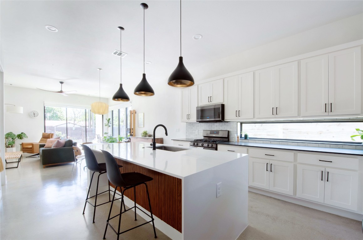 a kitchen with kitchen island granite countertop a sink a stove a dining table and chairs