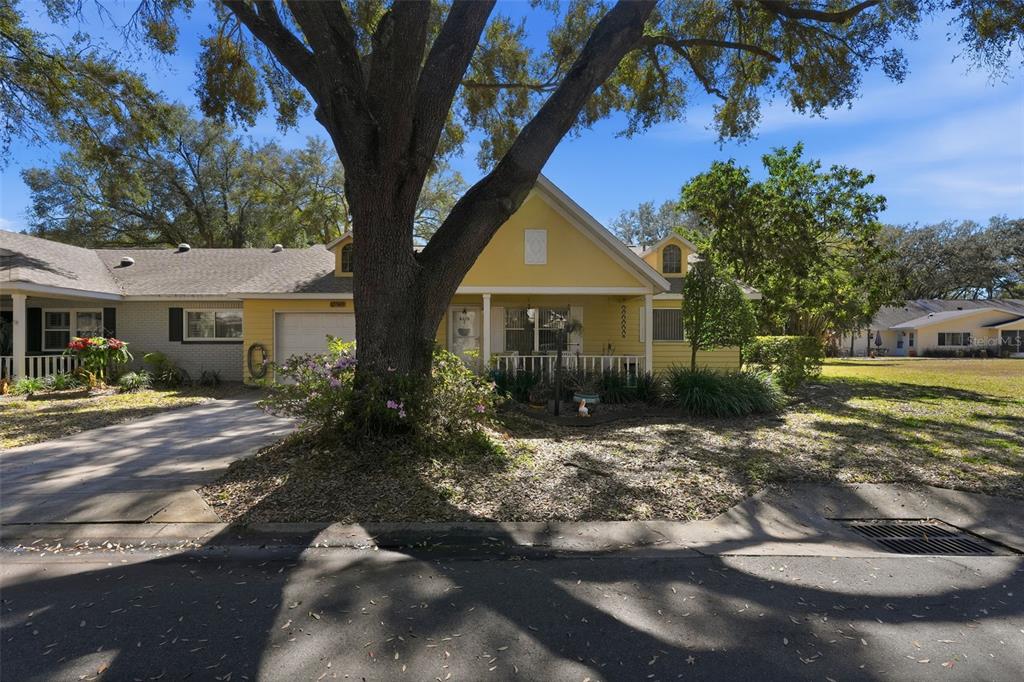 8556 Southwest 90th Lane, Unit F Ocala, FL 34481 - Photo 29 of 34 a view of a white house with a yard plants and large tree