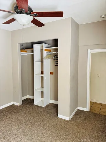 an empty room with closet and a ceiling fan