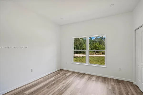 a view of an empty room with a window and wooden floor