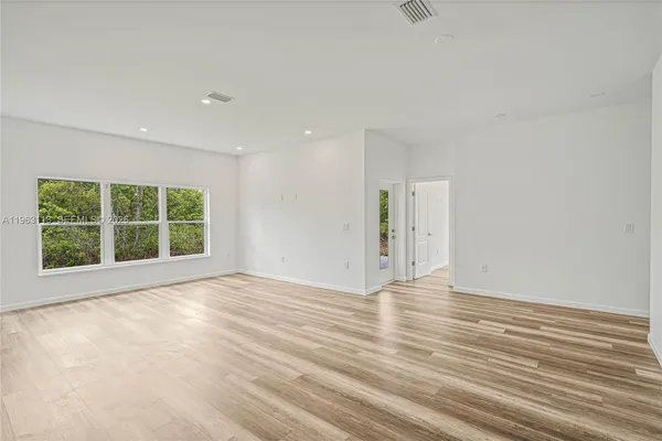 a view of an empty room with wooden floor and windows
