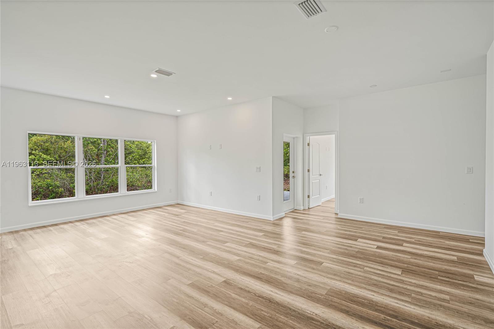 8001 Leonardo Street Sebring, FL 33872 - Photo 3 of 27 a view of an empty room with wooden floor and windows