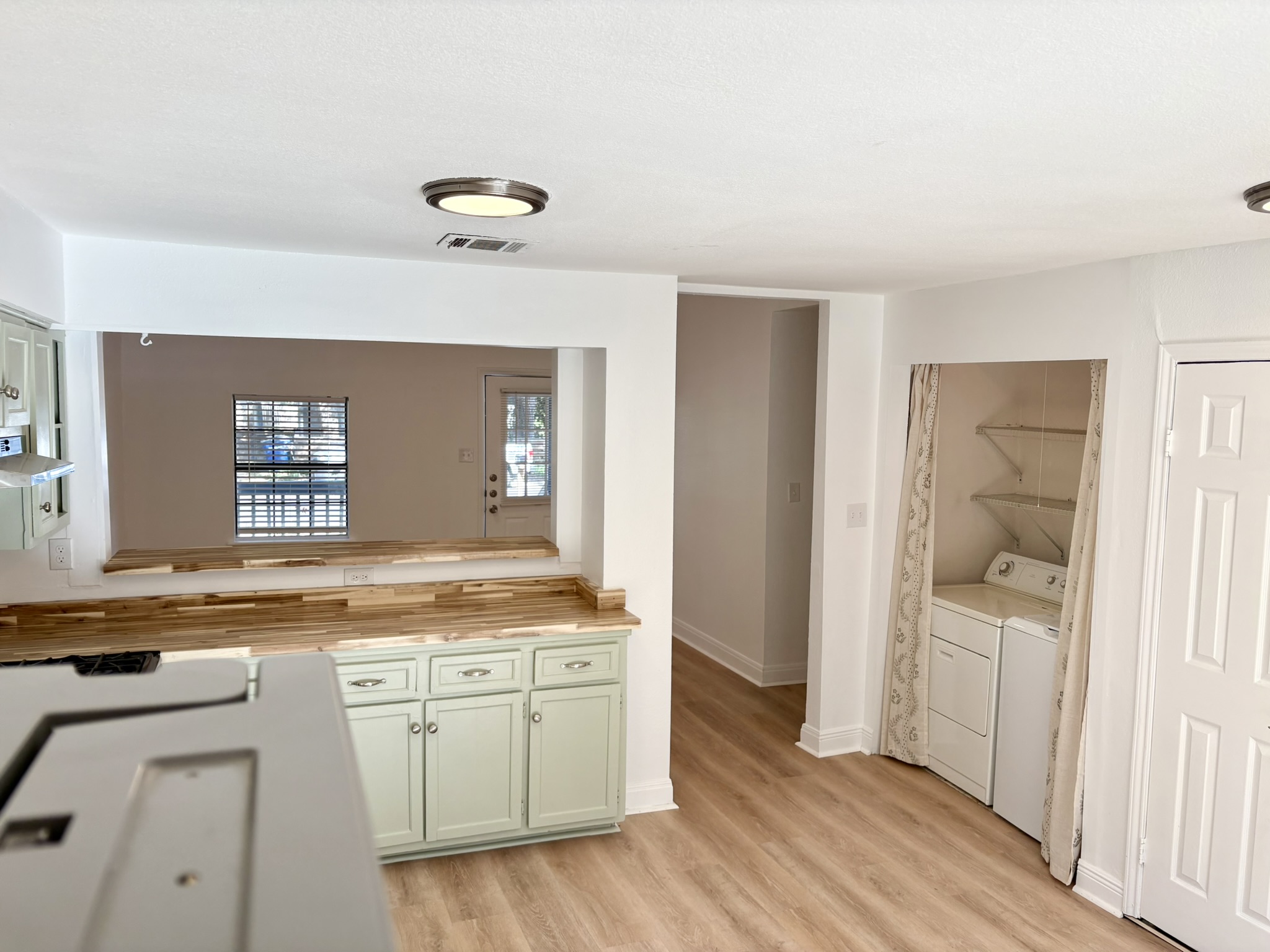 Undisclosed Address Austin, TX 78721 - Photo 5 of 28 Butcher block countertops and updated cabinetry accent this versatile kitchen space with adjacent laundry hookups.