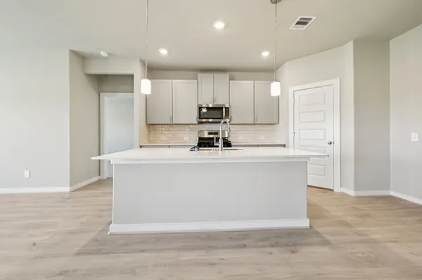 a kitchen with kitchen island a sink a stove a refrigerator and white cabinets