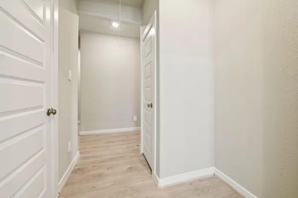 a view of a hallway with wooden floor and a bathroom
