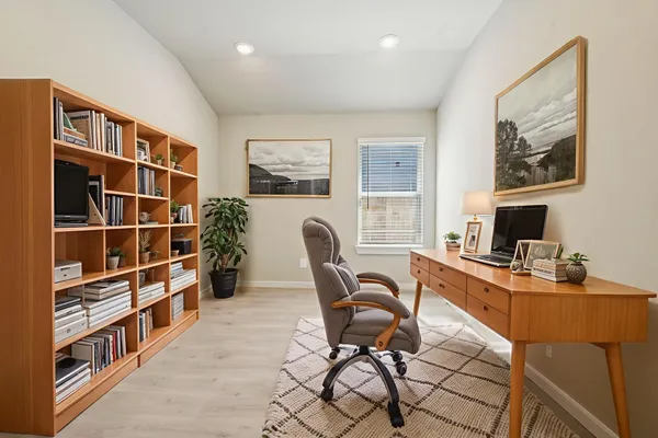 a work room with furniture a bookshelf and a window