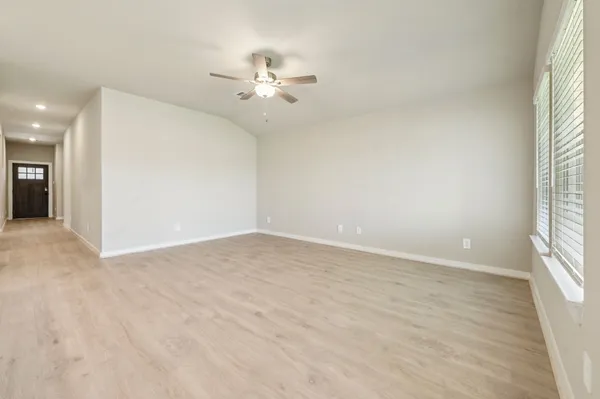 an empty room with windows and chandelier fan