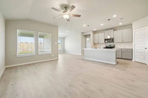 a view of a kitchen with kitchen island wooden floor and stainless steel appliances
