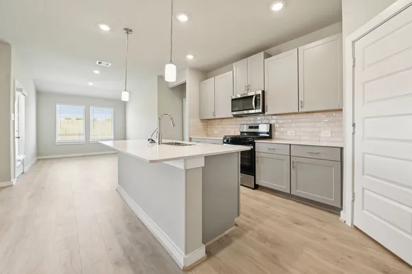 a kitchen with kitchen island sink stove and cabinets