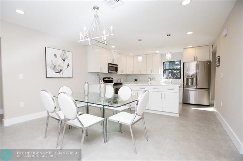 a kitchen with kitchen island a refrigerator cabinets a dining table and chairs