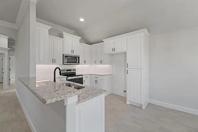 a kitchen with granite countertop white cabinets and stainless steel appliances