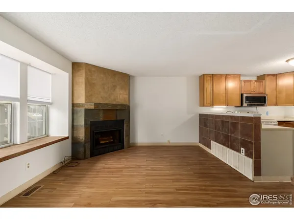 a view of empty room with kitchen and fireplace