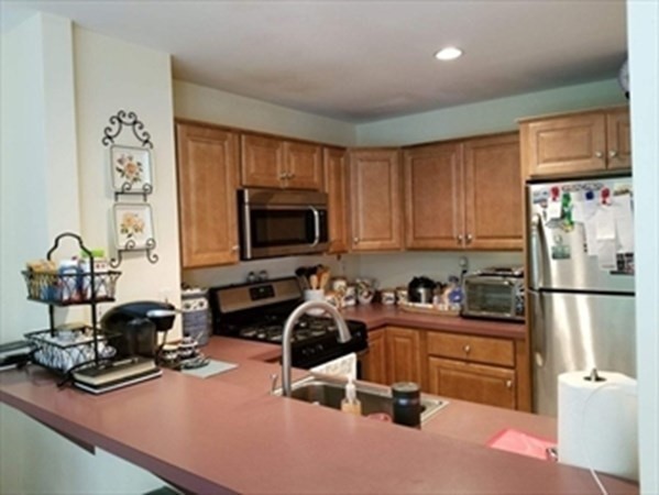 12 N Commons, Unit L Lincoln, MA 01773 - Photo 16 of 25 a kitchen with granite countertop a stove a sink and a refrigerator