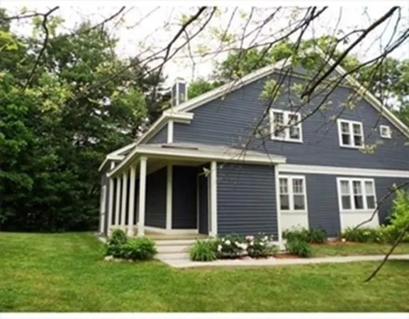 a view of brick house with a yard potted plants and large trees